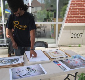 Hollowell’s brother, Freeze, arranges prints for sale at the Southeast Area Farmers’ Market Summer Celebration. 